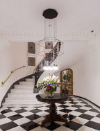 Octagonal wireframe pendant over a round table of flowers at the foot of a marble staircase, from Clérachic.