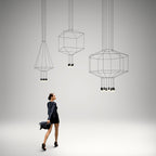 Three Clérachic wireframe pendants in cone, cube and octagon shapes, with a woman in a black dress walking below them.