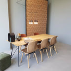 Wireframe pendant with lit heads above an oak dining table and tan chairs, against a patterned panel, from Clérachic.