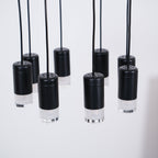 Close view of black cylindrical light heads with perforated tops and frosted bases, hanging on black cables, from Clérachic.