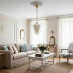 Clérachic pendant with a pleated shade hanging in a cream sitting room, above a white coffee table and a linen sofa.