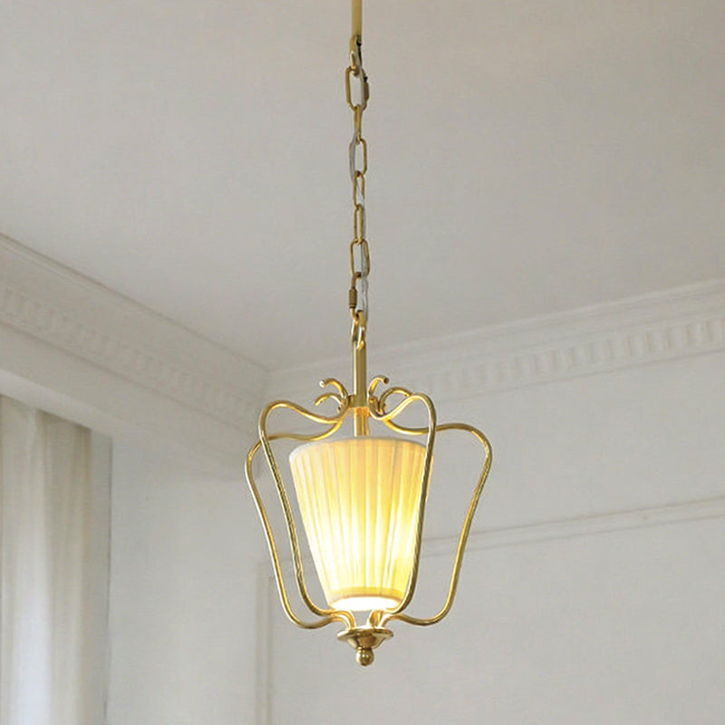 Clérachic pendant on a brass chain with a vertically pleated shade glowing, below white ceiling mouldings.