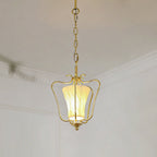Lit Clérachic brass pendant with a diagonally pleated shade, hanging below white ceiling mouldings.