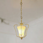 Clérachic brass pendant with a glowing twisted-pleat shade, hung from a chain beneath a white cornice.