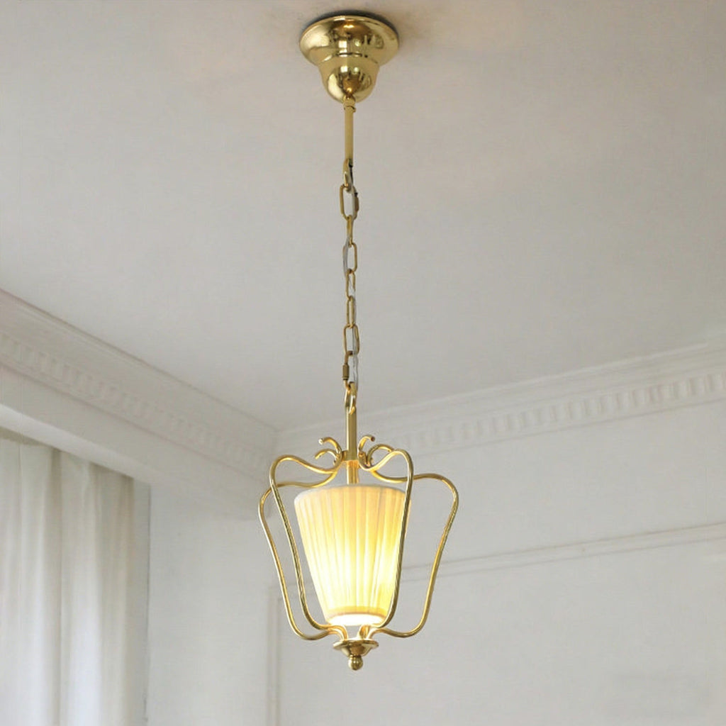 Lit Clérachic brass pendant with a twisted-pleat shade, shown from below with its brass ceiling canopy at the top.
