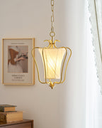 Clérachic brass pendant lit in front of a framed print, with a lace curtain and a wooden chest at the edge.