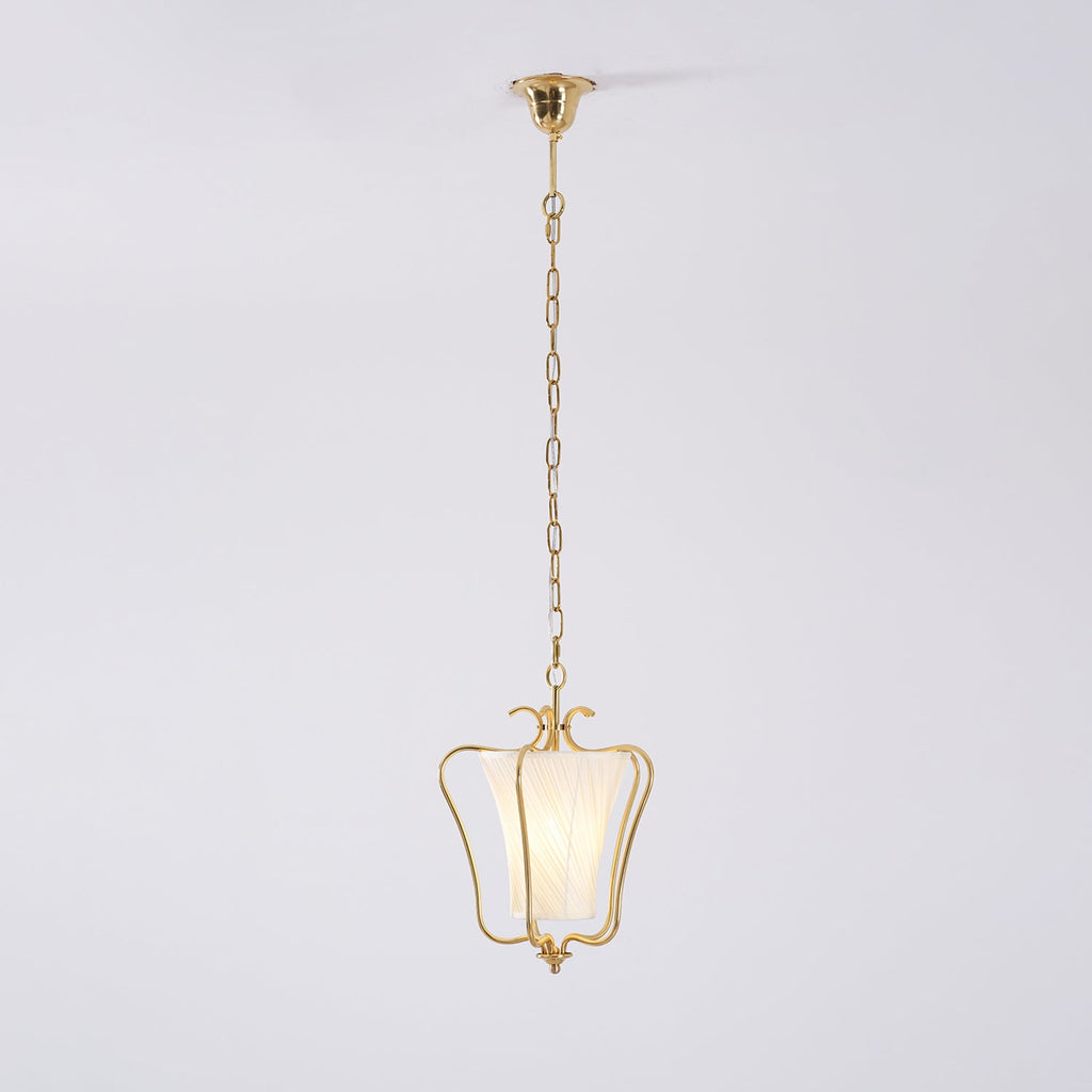 Clérachic pendant on its slim brass chain and ceiling canopy, with a twisted-pleat shade, on a pale backdrop.