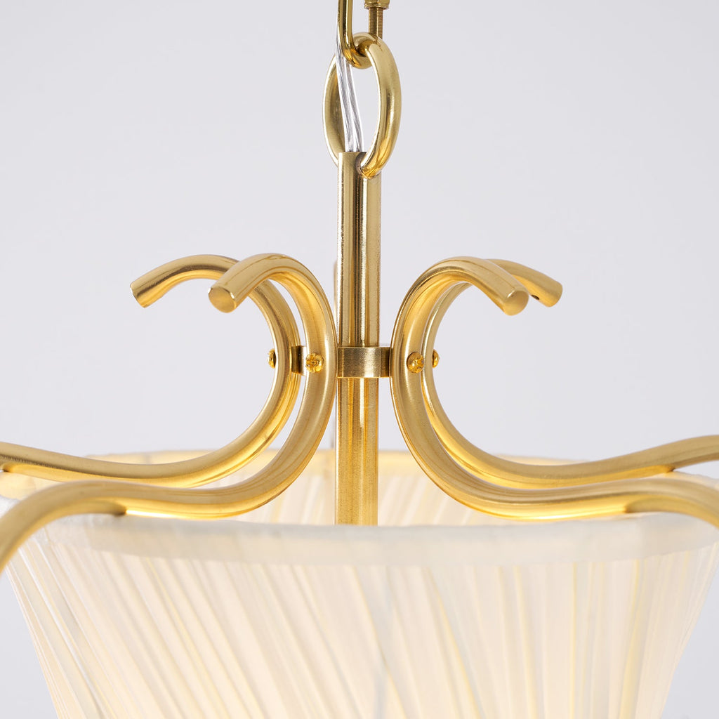 Close view of the curled brass crown, chain ring and top of the pleated shade on this Clérachic pendant.