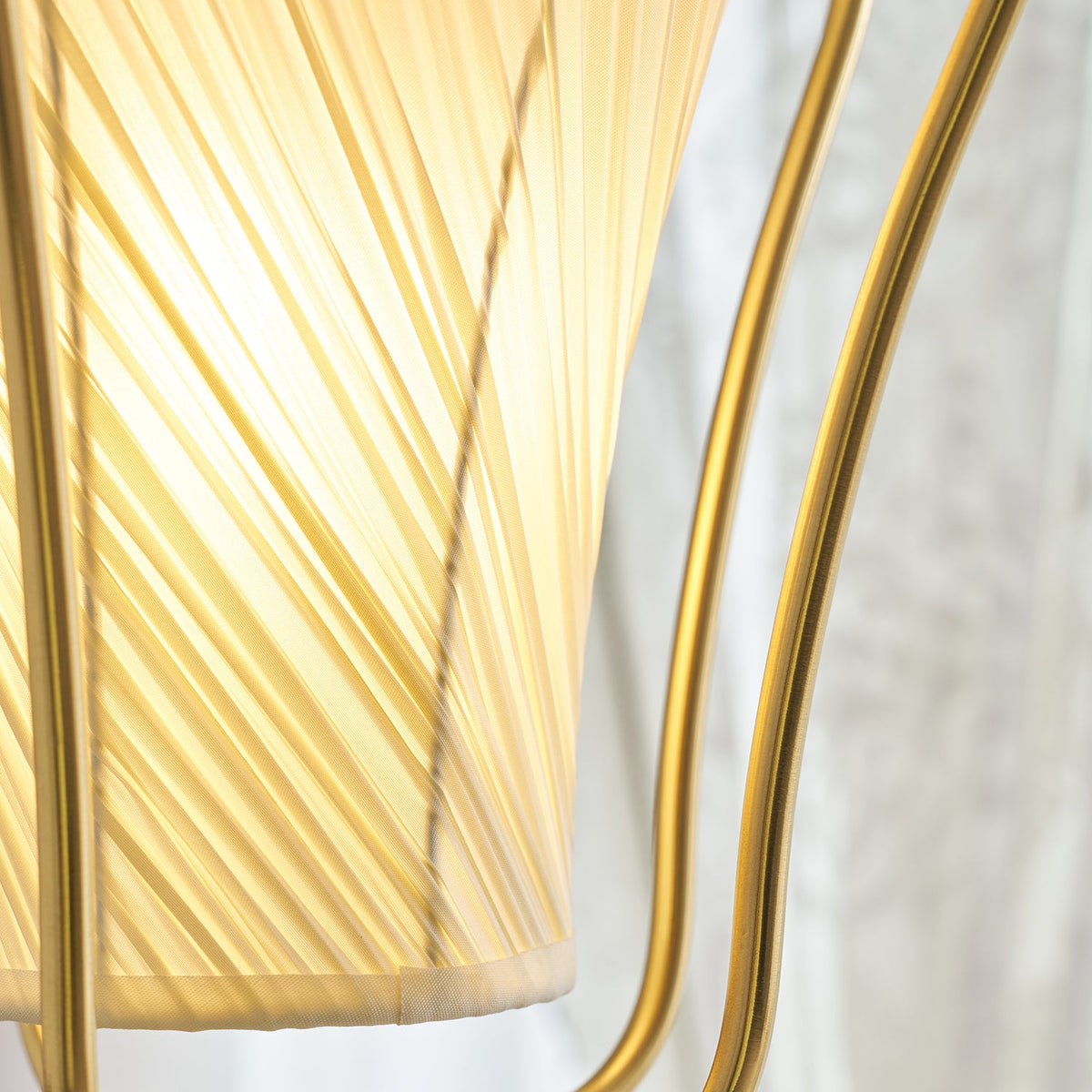 Close view of the glowing, finely twisted pleats of the shade on this Clérachic pendant, held by the brass frame.