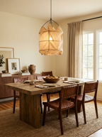 Above a rustic wood dining table, this Clérachic pendant glows beside leather-back chairs and sheer curtains.