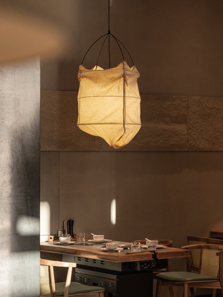 A close angle on the wire ribs and beige fabric of this Clérachic pendant, glowing against a stone wall.