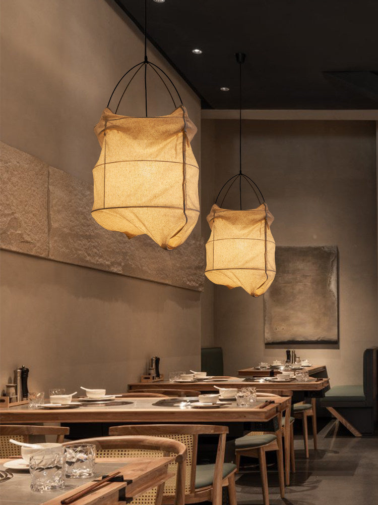 Two of this Clérachic pendant hang lit side by side above wood café tables in a dim dining room.