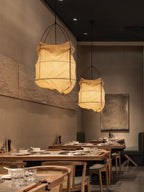 Two of this Clérachic pendant hang lit side by side above wood café tables in a dim dining room.