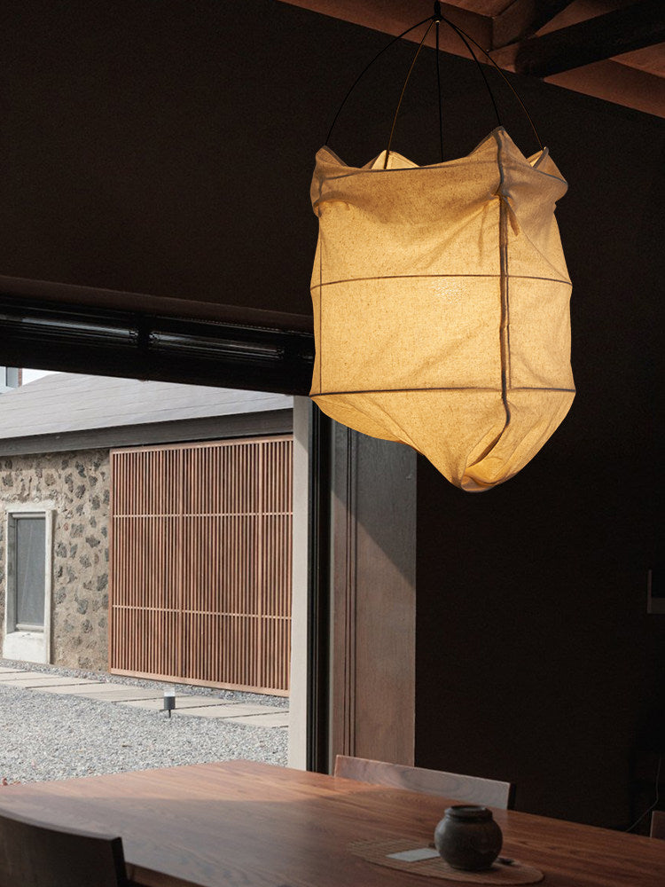 Glowing at night against dark ceiling beams, this Clérachic pendant overlooks an outdoor courtyard through open doors.