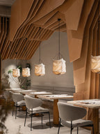 A row of this Clérachic pendant lights café tables beneath a sculpted wood ceiling in a restaurant.