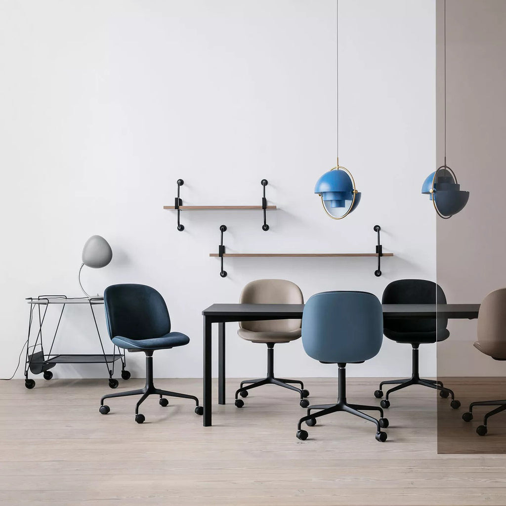 Two blue-shaded Clérachic pendants over a table with navy and grey chairs, against a white wall with wall shelves.