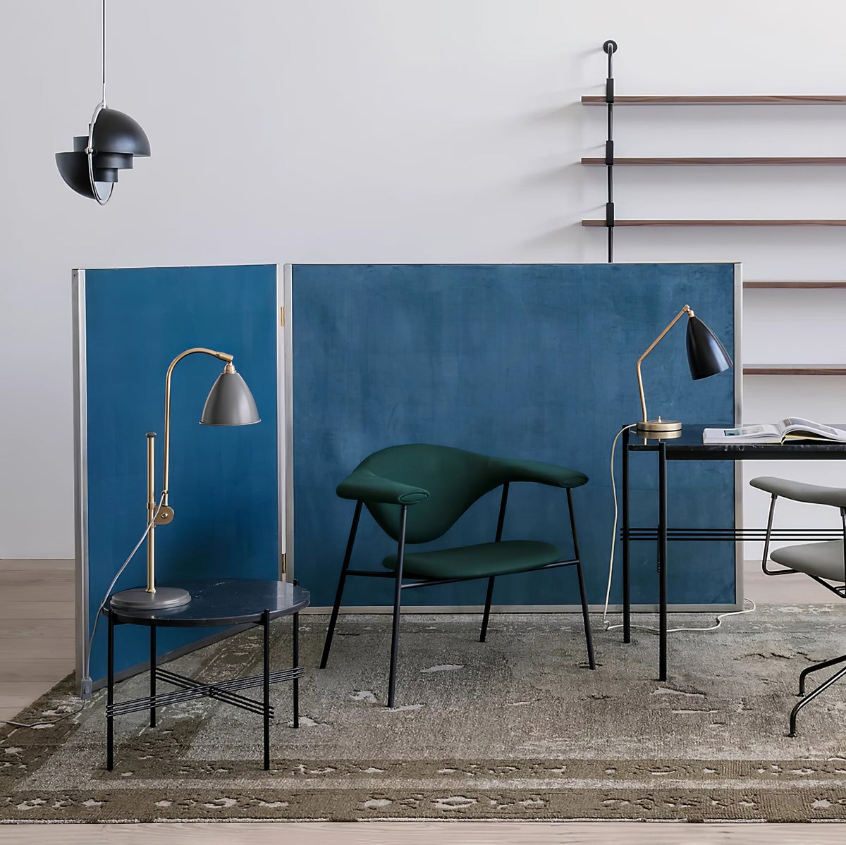 Black Clérachic pendant high in a corner next to a blue partition, a green armchair and two desk lamps.