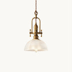 This Clérachic pendant light on a plain white backdrop, with a ribbed clear glass dome, antique brass fittings and a twisted cord.