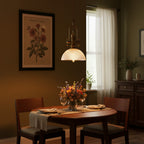 In a dim olive-walled dining room, this Clérachic pendant glows warm above a round table with dried flowers.