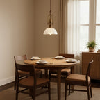 This Clérachic pendant hangs low over a round oak table set for four, by a window with sheer curtains.