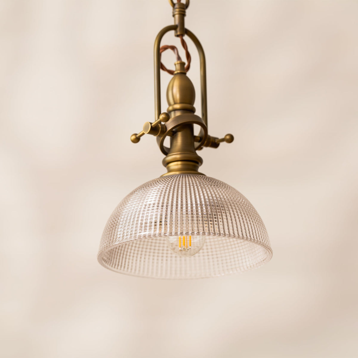 Clérachic pendant seen slightly from below, with the filament bulb showing through the clear ribbed glass dome.