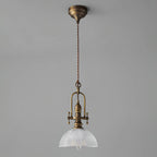 Clérachic pendant on a grey backdrop, with its antique brass canopy, a long twisted cord and a clear glass dome.