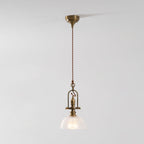 A Clérachic pendant on a light grey backdrop, with its brass canopy, a long cord and a ribbed glass dome.