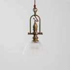 Close view of the brass cradle and the clear ribbed glass dome on this Clérachic pendant, unlit.