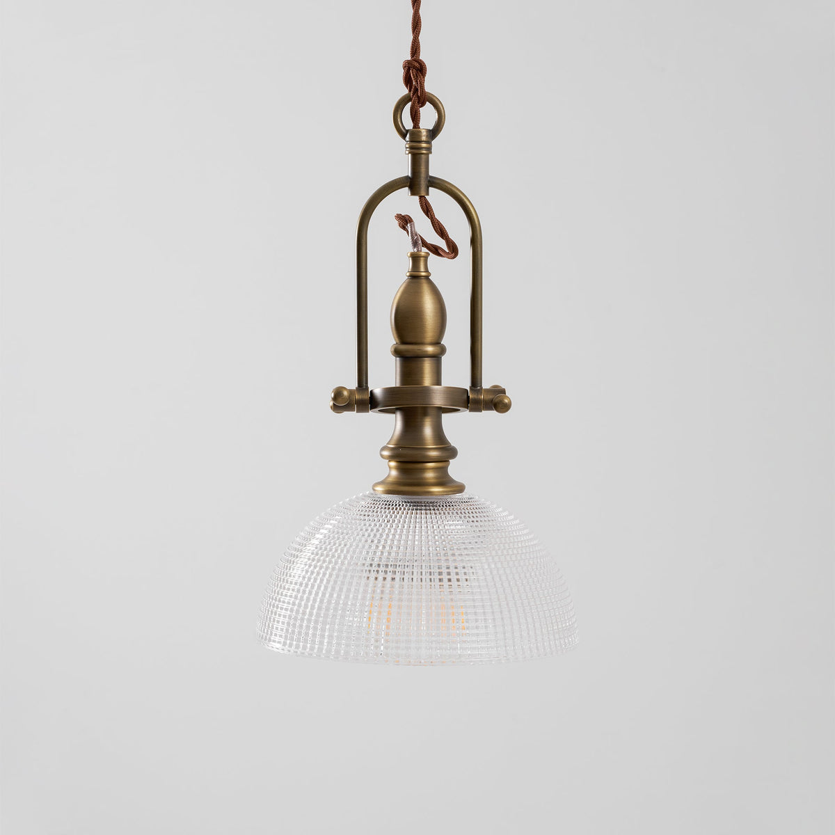 Close view of the brass cradle and the clear ribbed glass dome on this Clérachic pendant, unlit.