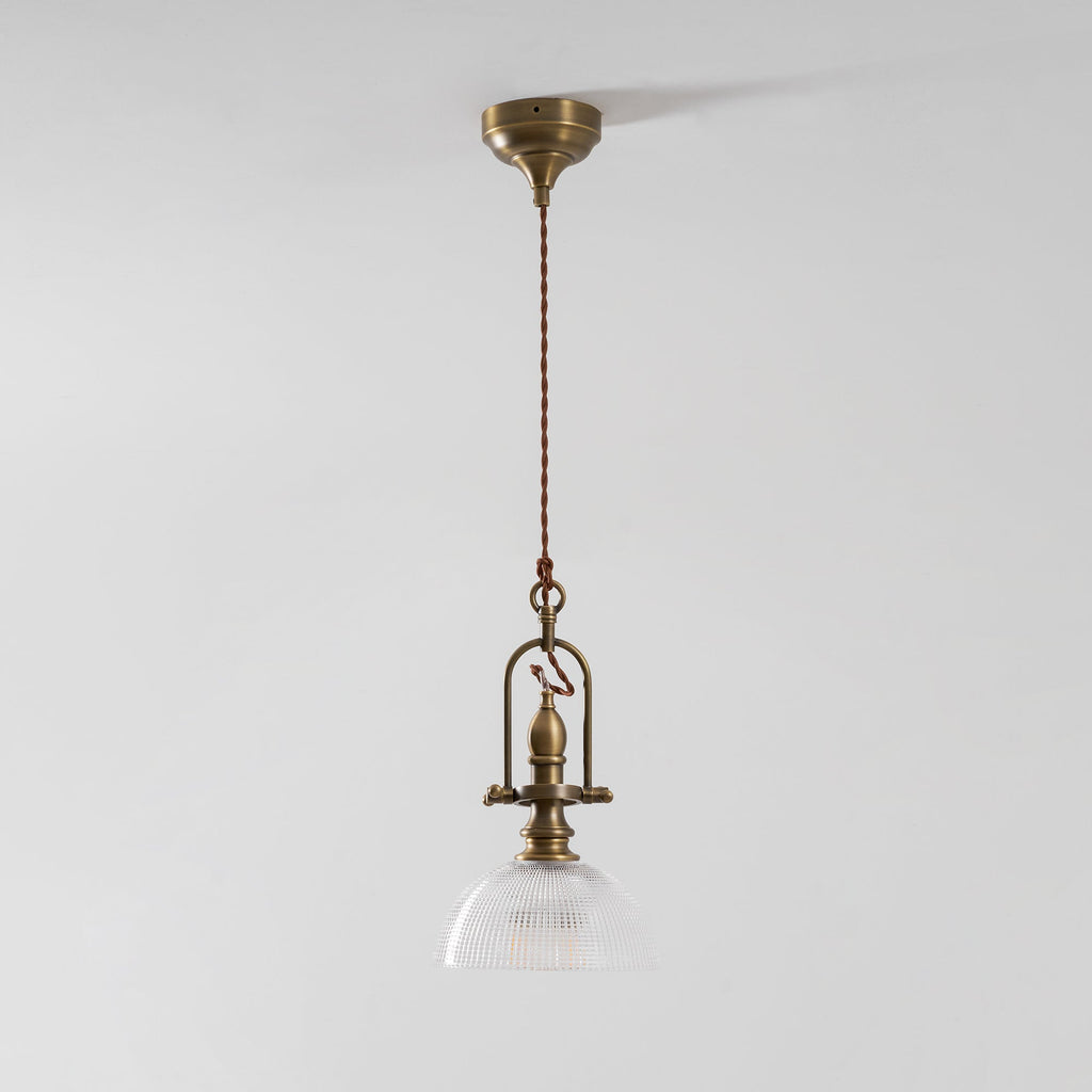 Clérachic pendant from a distance on a pale wall, with a brass canopy, a twisted cord and a small glass dome.