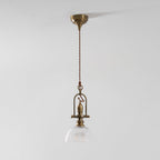Clérachic pendant from a distance on a pale wall, with a brass canopy, a twisted cord and a small glass dome.