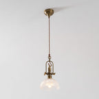 Clérachic pendant lit against a pale grey wall, with a brass canopy, a twisted cord and a ribbed glass dome.