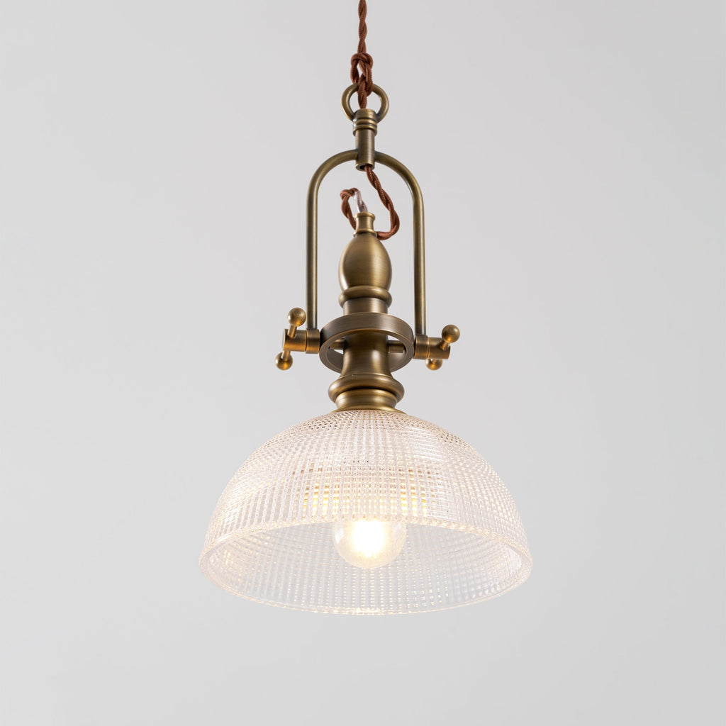 Clérachic pendant seen from the front, with an open brass cradle and a clear dome, and a filament bulb at its centre.