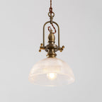 Clérachic pendant seen from the front, with an open brass cradle and a clear dome, and a filament bulb at its centre.