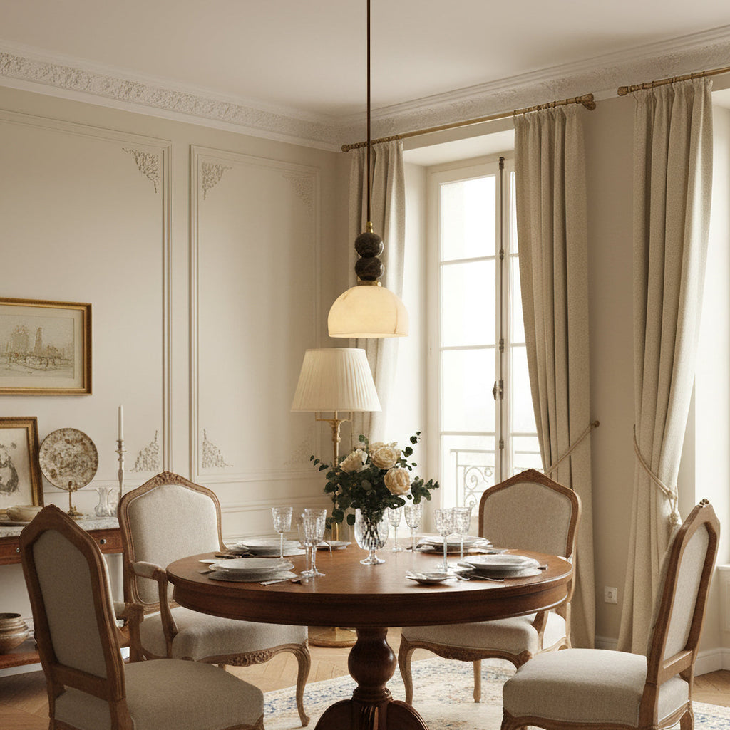 Clérachic pendant light above a round wooden dining table laid for a meal, in a classic room with tall windows and curtains.