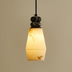 Lit Clérachic pendant light with a tapered, two-part faux alabaster shade and a black cord, on a warm beige backdrop.