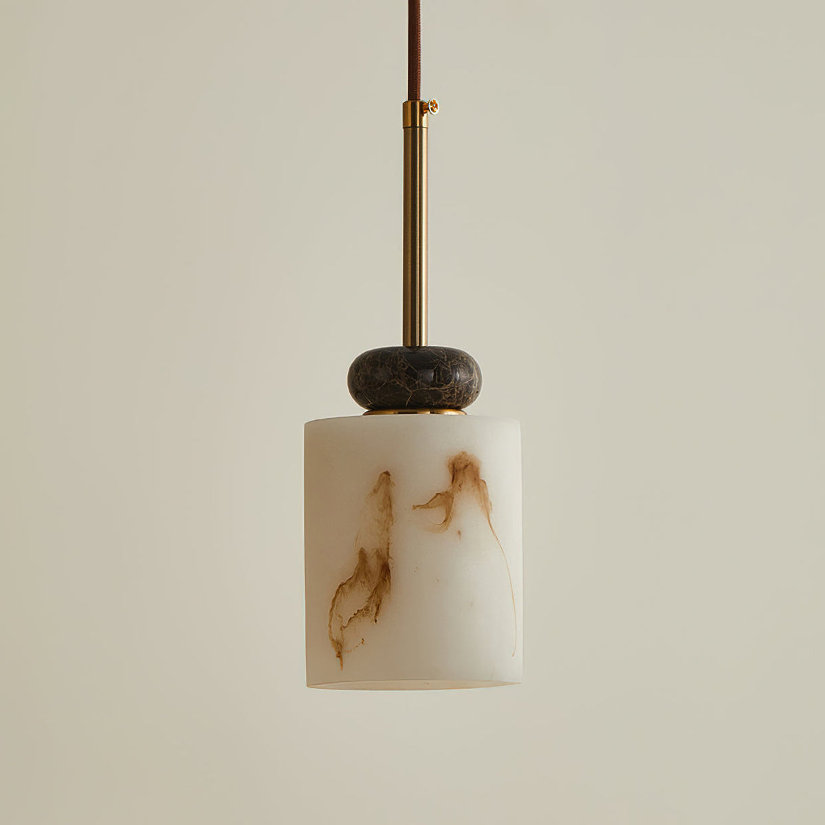 Short cylinder shade with veined stone under a single dark marble disc on this Clérachic pendant light, with a brass rod above.