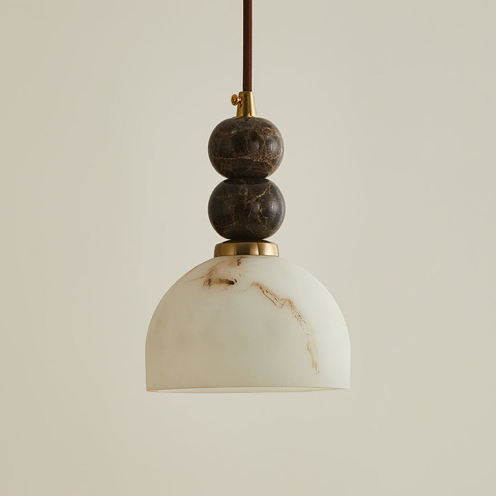 Unlit dome shade of faux alabaster hanging below two stacked dark marble spheres on this Clérachic pendant light.