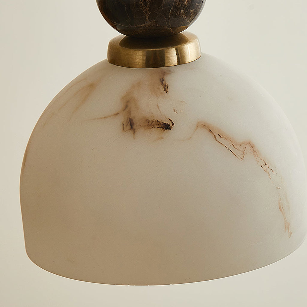 Close view of the underside of the veined dome shade, below a brass collar and dark marble sphere, on this Clérachic pendant light.