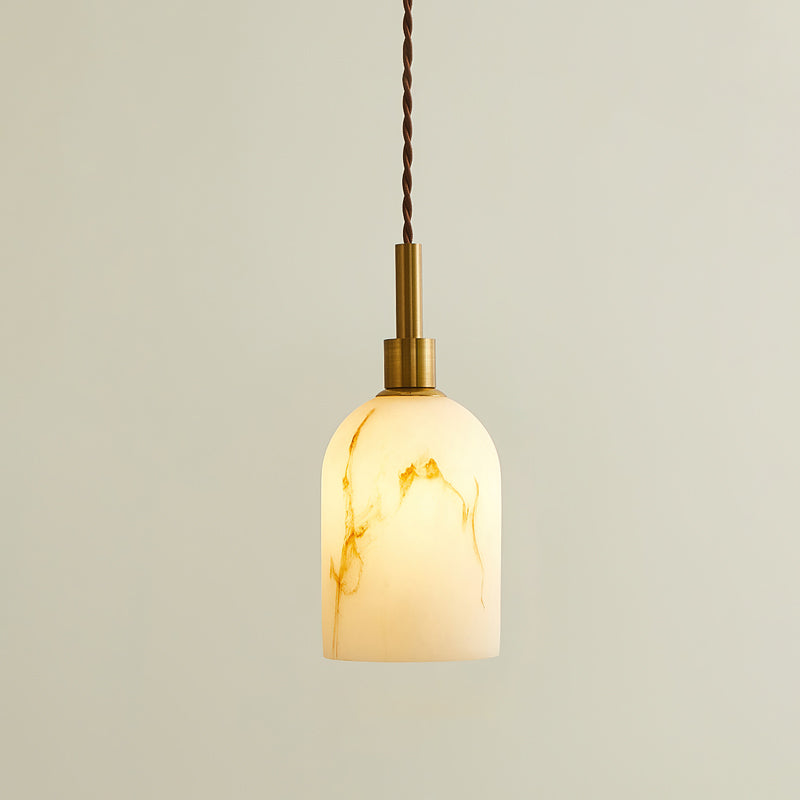 Lit Clérachic pendant light with a rounded cylinder shade, glowing warm with brown veining and a brass cap on a twisted cord.