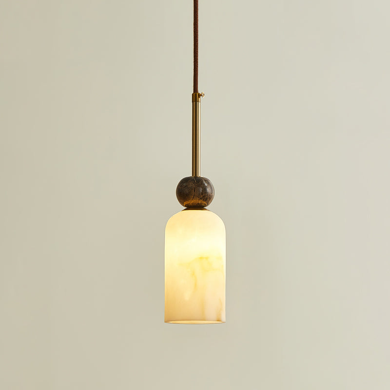 This Clérachic pendant light glows softly through its rounded cylinder shade, with a single marble sphere and a brass rod above.
