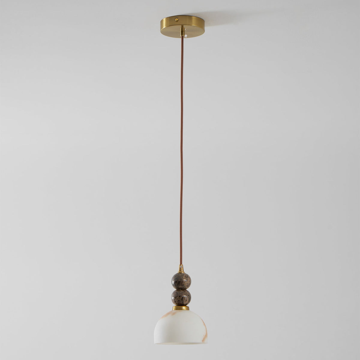 Full length of this Clérachic pendant light, a thin brown cord running from a brass ceiling plate down to a small dome shade.
