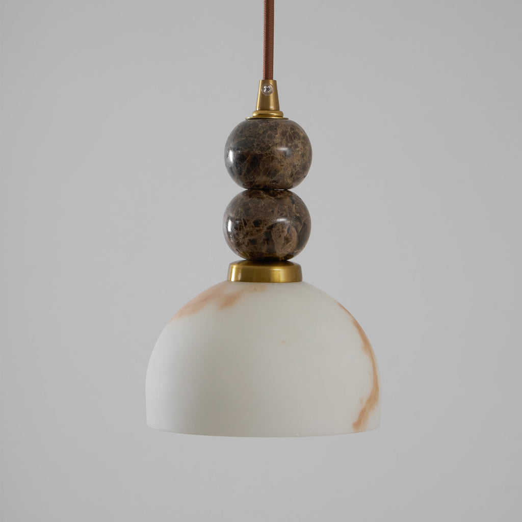 Unlit Clérachic pendant light with a dome shade and two dark marble spheres on a brown cord, against a plain grey backdrop.