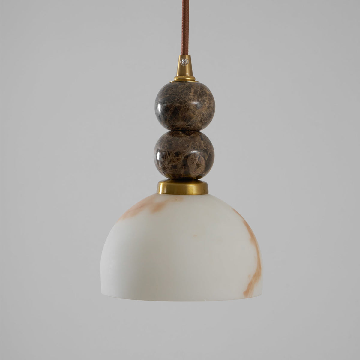 Unlit Clérachic pendant light with a dome shade and two dark marble spheres on a brown cord, against a plain grey backdrop.