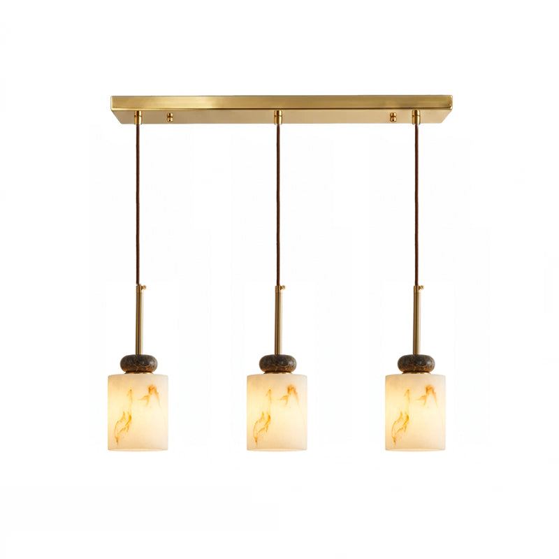 Three short cylinder shades with dark marble discs hang from the brass bar of this Clérachic pendant light.