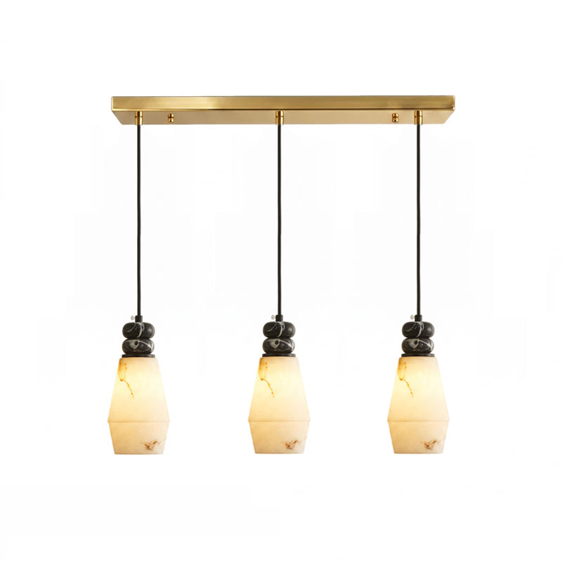 Three tapered, faceted shades with black cords hang from the brass bar of this Clérachic 3-light pendant light.