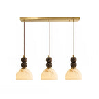 Three dome shades with paired dark marble spheres hang from the brass bar on this Clérachic 3-light pendant light.