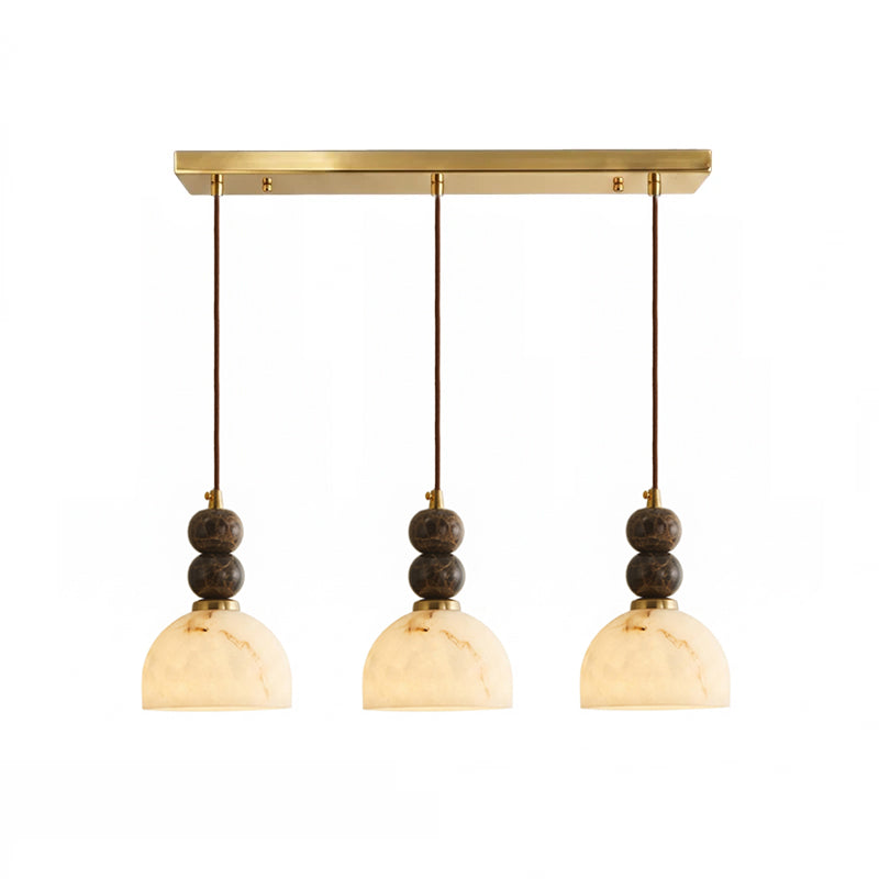 Three dome shades with paired dark marble spheres hang from the brass bar on this Clérachic 3-light pendant light.