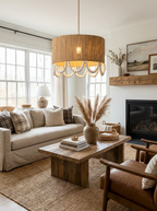 In a living room with a jute rug and stone fireplace, this Clérachic pendant hangs lit above a wood coffee table.