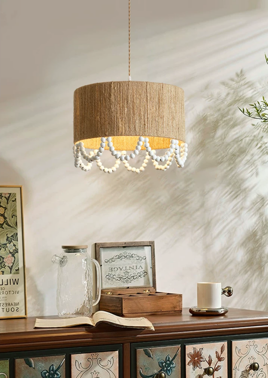 Dappled sunlight falls across this Clérachic pendant, lit above a wood sideboard styled with jars and books.
